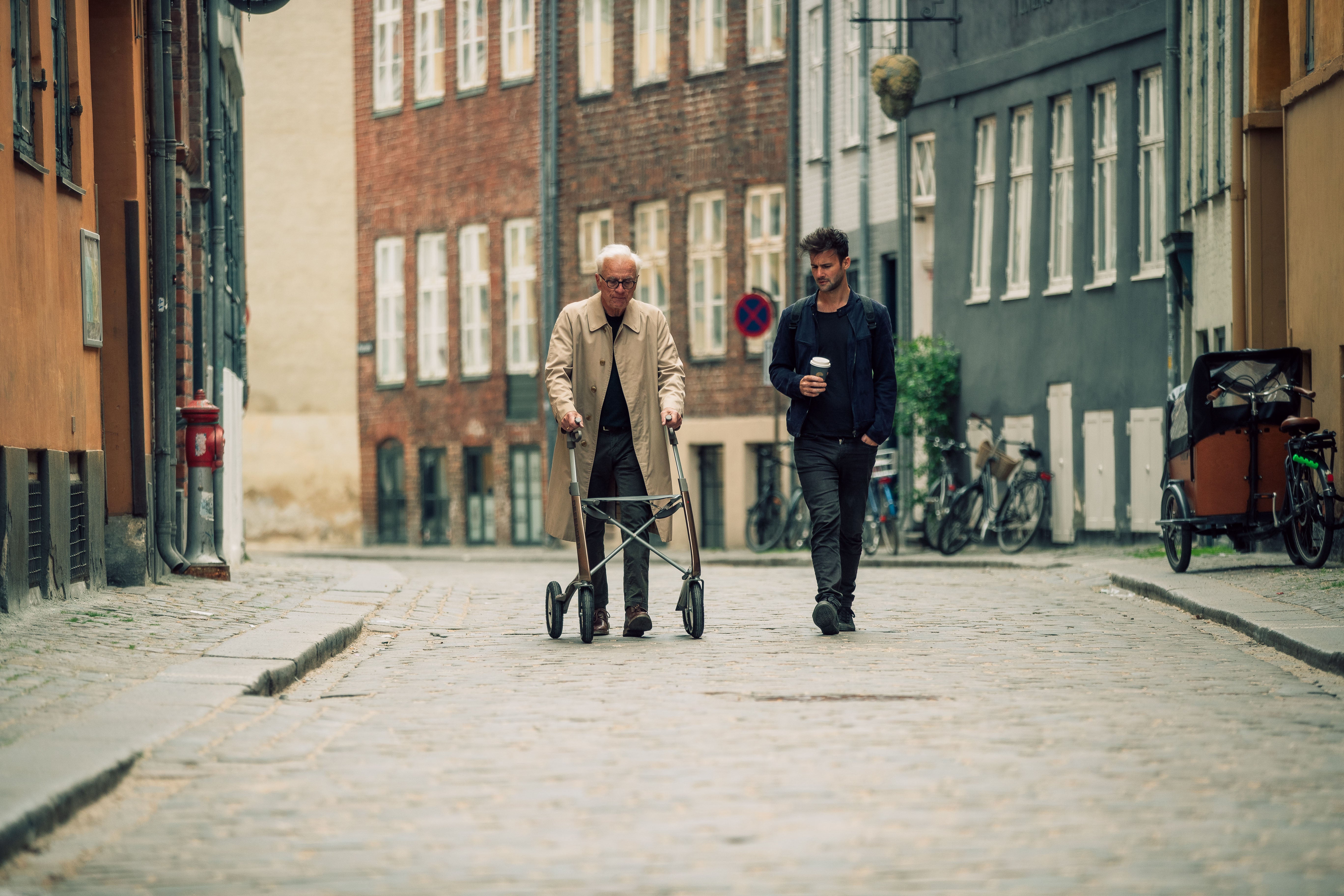 Person using a Bentley Brown byACRE Carbon Overland rollator on a cobblestone street